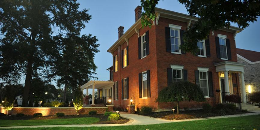 Honors House pictured with a few windows lit just before dusk